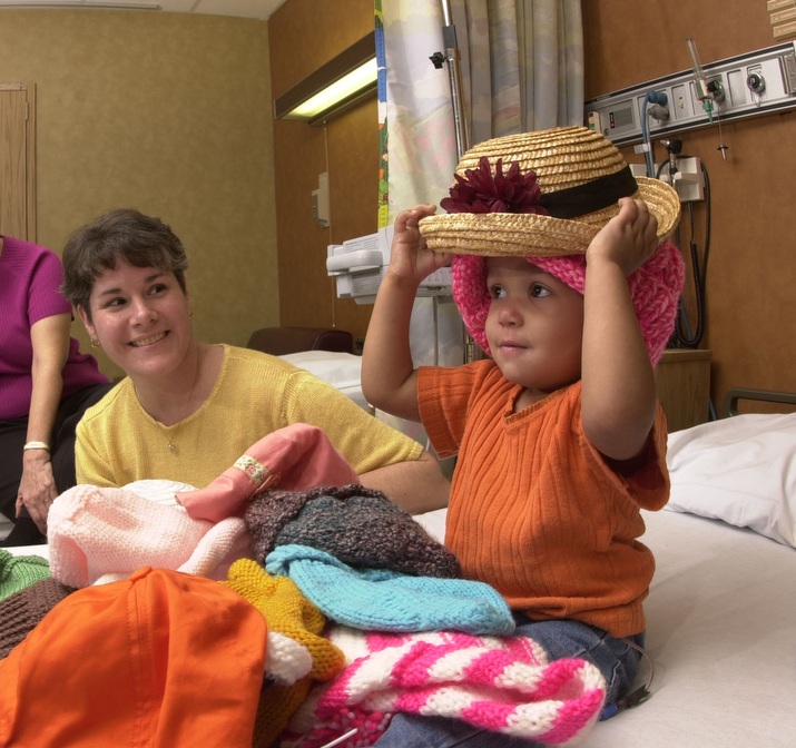 22 month old girl trying out hats to wear after chemotherapy